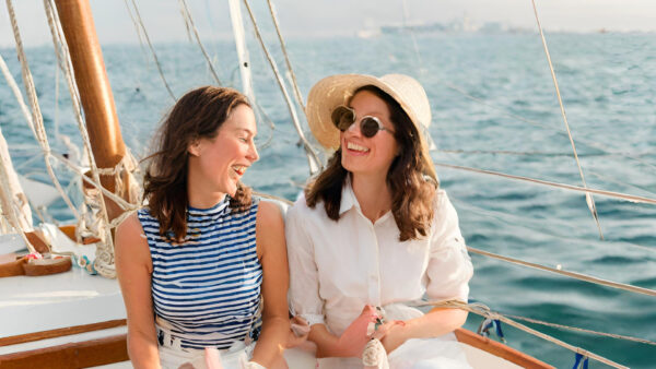 Two women enjoying the view while sitting on the deck of a sailboat, surrounded by calm waters